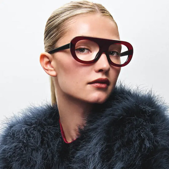 Jeune femme portant de grandes lunettes rouges design lors d’un examen de la vue à Saint-Lambert, en gros plan avec manteau texturé.