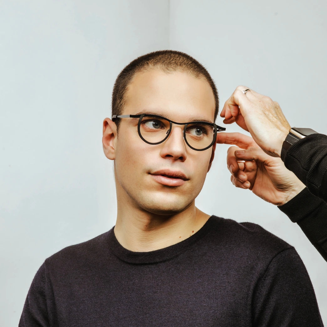 Jeune homme avec des yeux verts qui porte des lunettes noirs